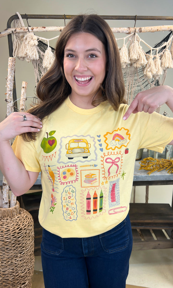 Cheerful woman showcasing the All the Teacher Things Graphic Shirt with fun school-themed designs, perfect for educators.