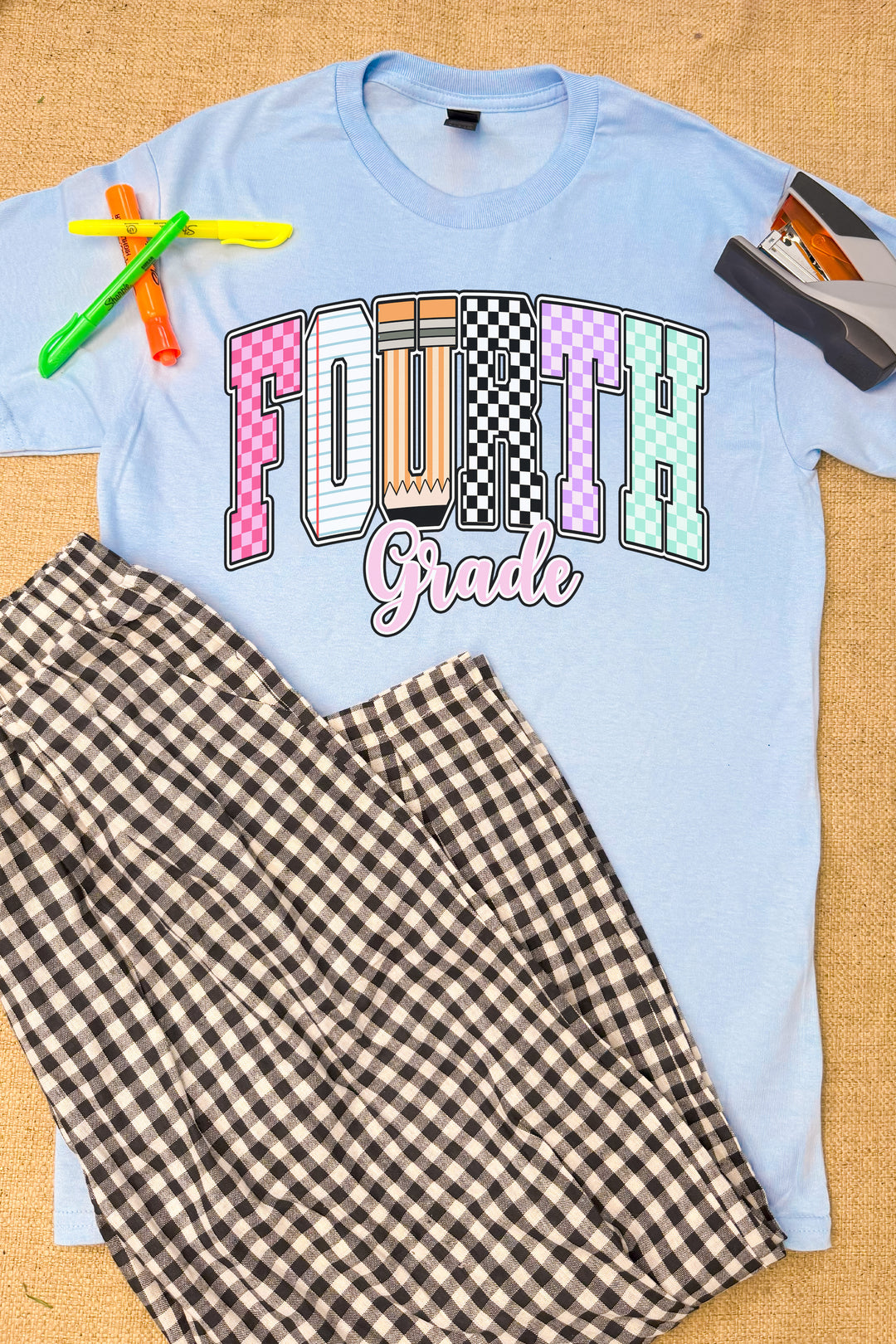Stylish Checkerboard Grade Level Graphic T-Shirt for kids, featuring "FOURTH Grade" in vibrant colors. Perfect for school!
