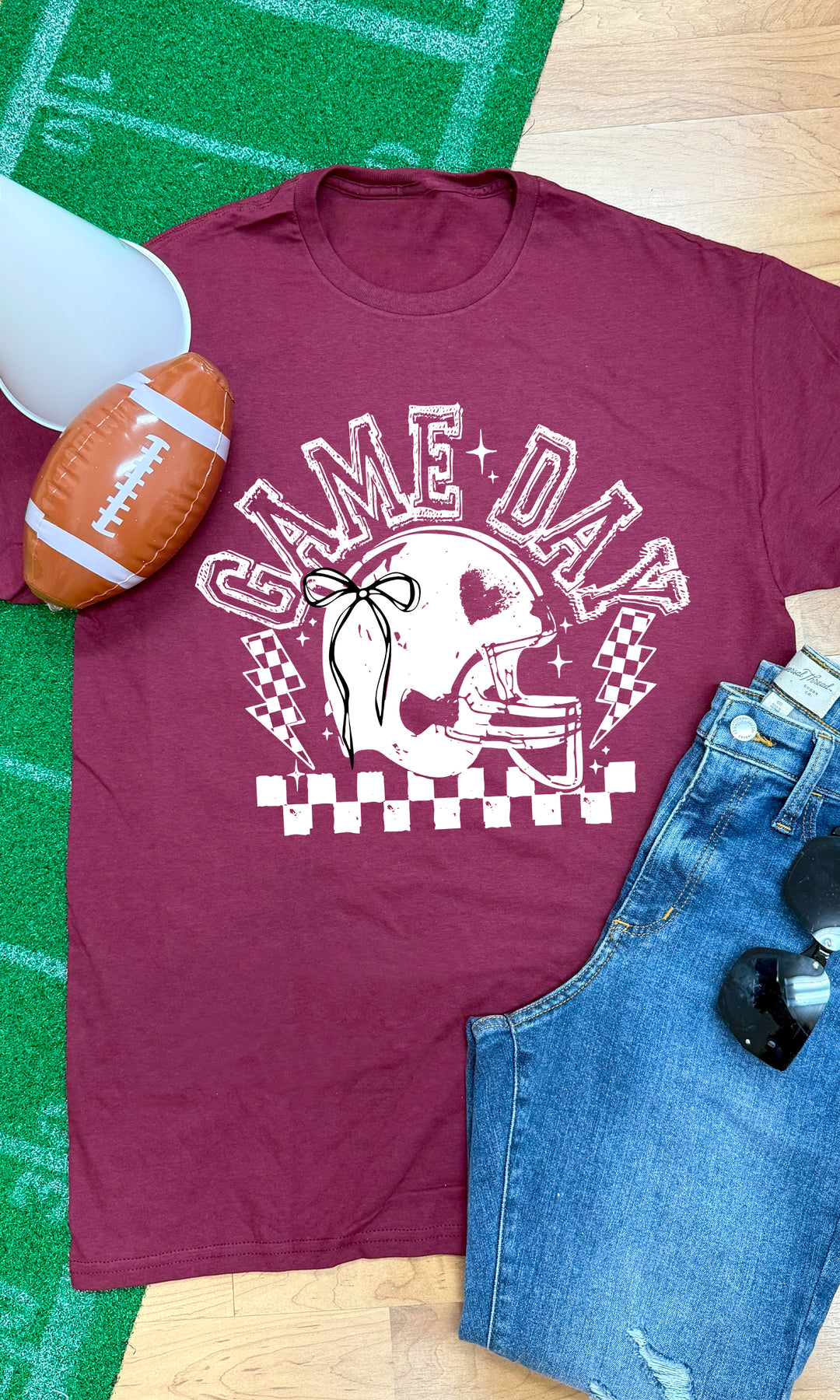 Maroon Game Day Football Bow Graphic T-Shirt featuring a stylish helmet design, perfect for football fans.