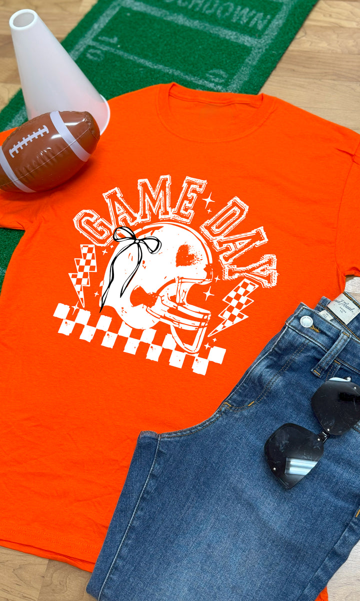 Bright orange Game Day Football Bow Graphic T-Shirt displayed with jeans and sunglasses, perfect for game day style.
