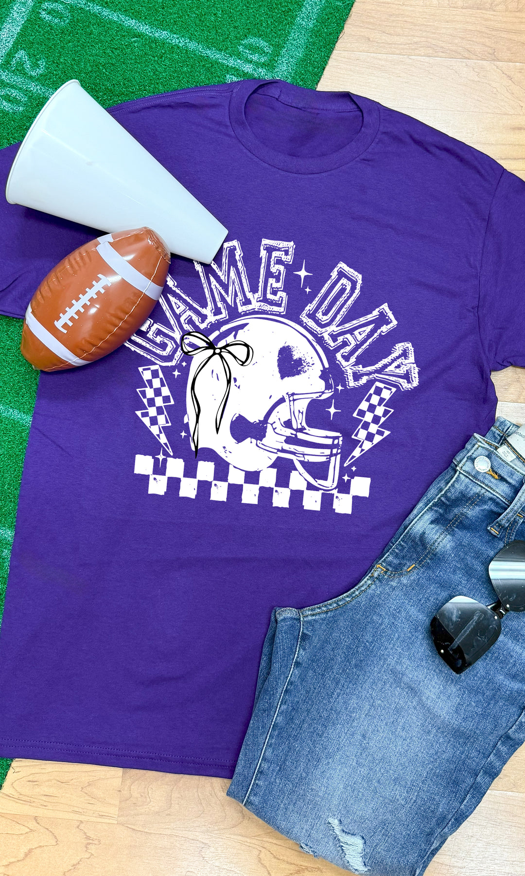 Purple Game Day Football Bow Graphic T-Shirt with helmet design, perfect for cheering on your team in style.