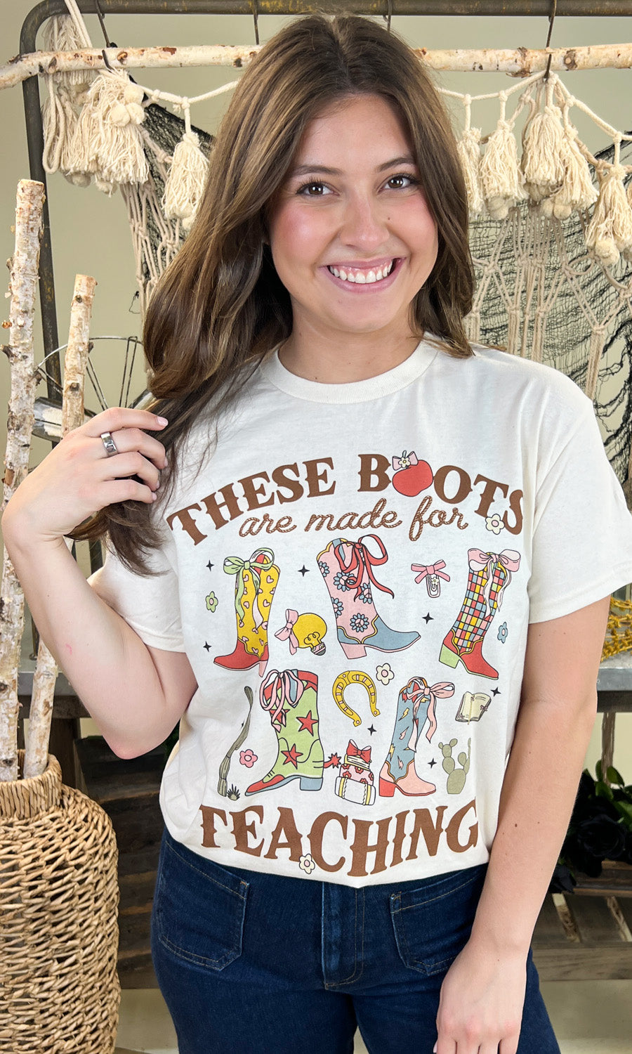 Stylish woman wearing the These Boots Were Made For Teaching Graphic Shirt, showcasing colorful boot designs.