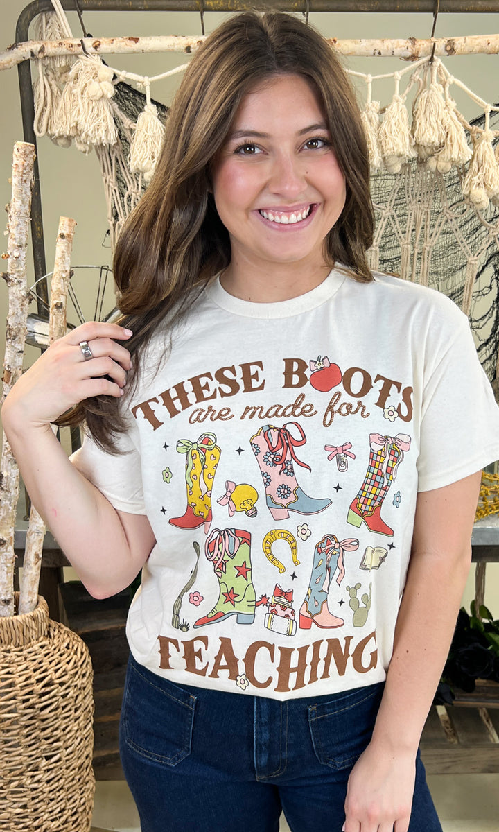 Stylish woman wearing the These Boots Were Made For Teaching Graphic Shirt, showcasing colorful boot designs.