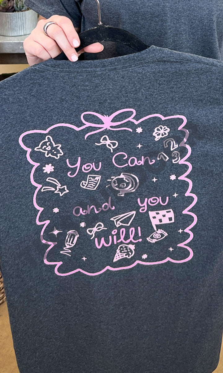 "You Can and You Will Teacher Graphic Shirt features motivational designs in pink on a dark background, perfect for educators."
