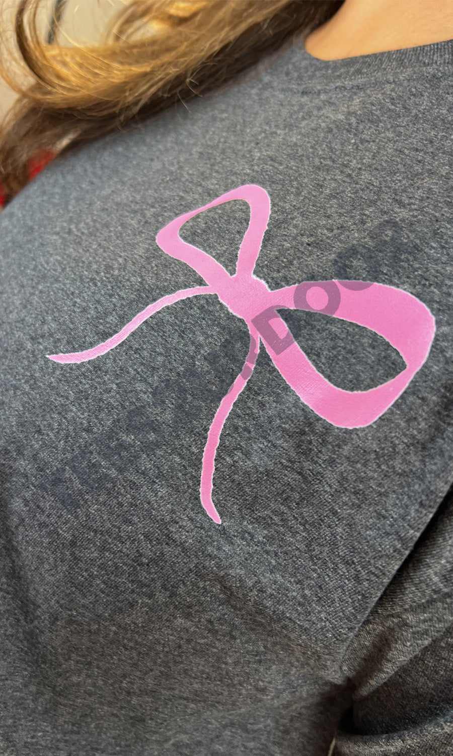 Stylish You Can and You Will Teacher Graphic Shirt featuring a bold pink bow design on a dark fabric background.
